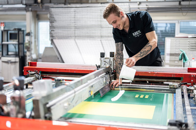 Ein Drucker, der Farbe auf ein Sieb in einer Siebdruckmaschine füllt